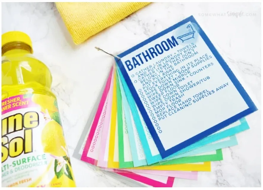 brightly framed chore card checklists by room with bottle of pine sol cleaner on left side