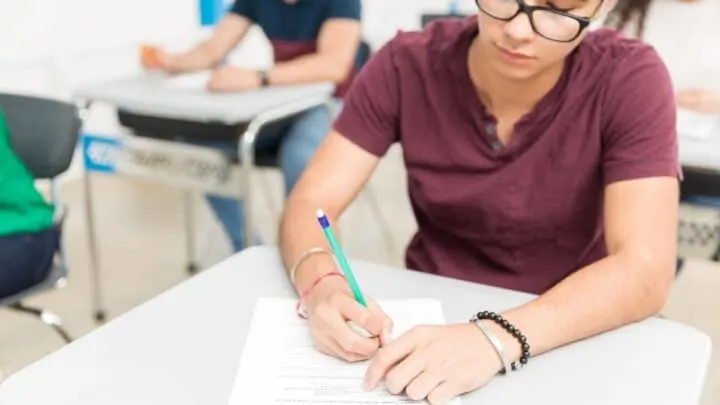 teen boy with bracelets, writing on journal topic for teen in class