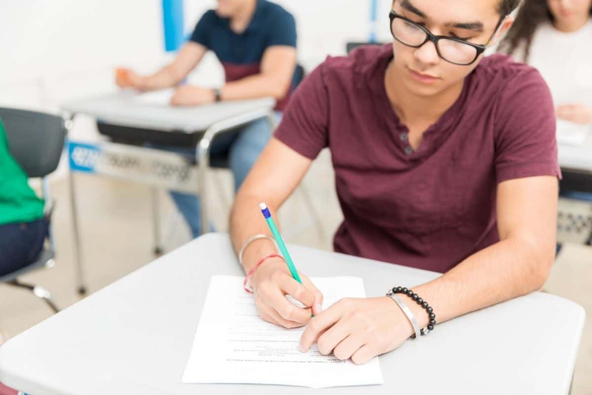 teen boy with bracelets, writing on journal topic for teen in class