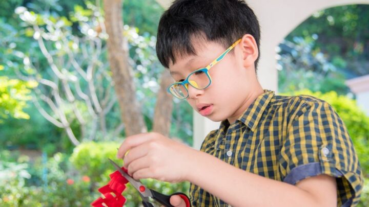boy with colorful glasses working on crafts to sell at school