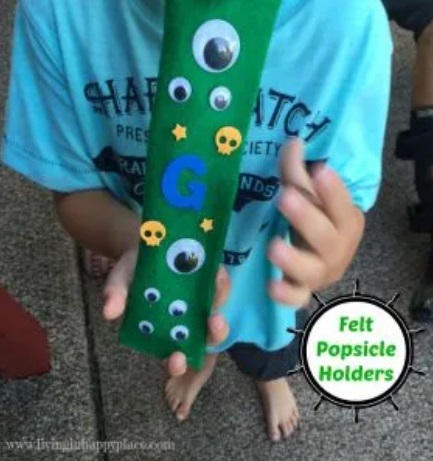 boy holding green felt freezer pops sleeve with googly eyes