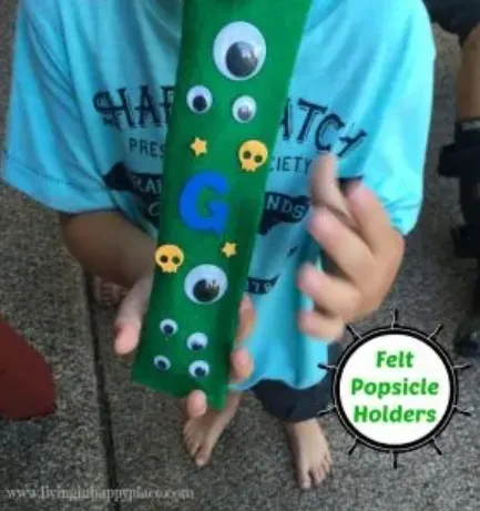 boy holding green felt freezer pops sleeve with googly eyes