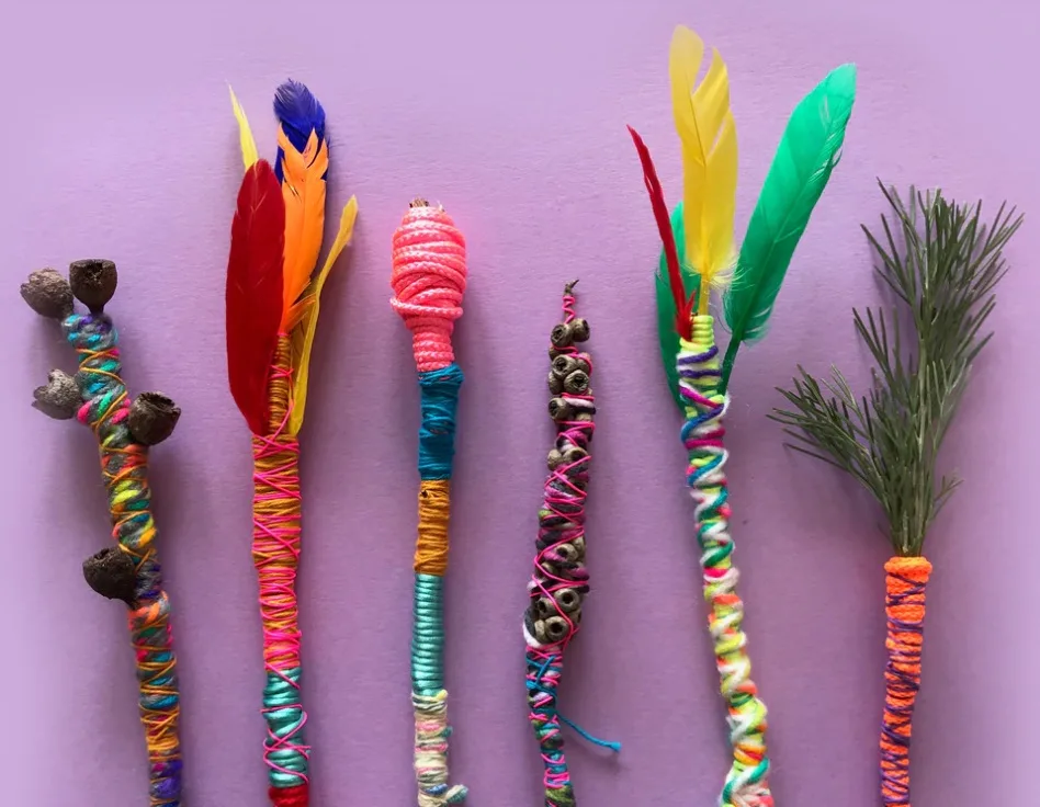 colorful thread-wrapped twigs with feathers on purple background