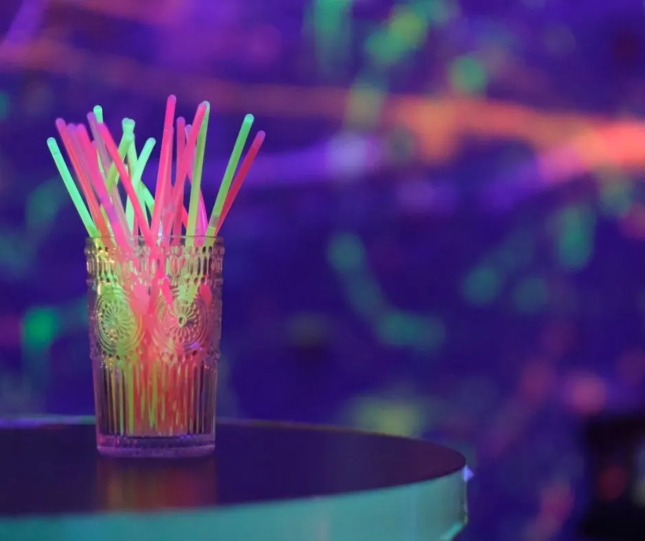 vase of glow sticks on a small round table in the dark