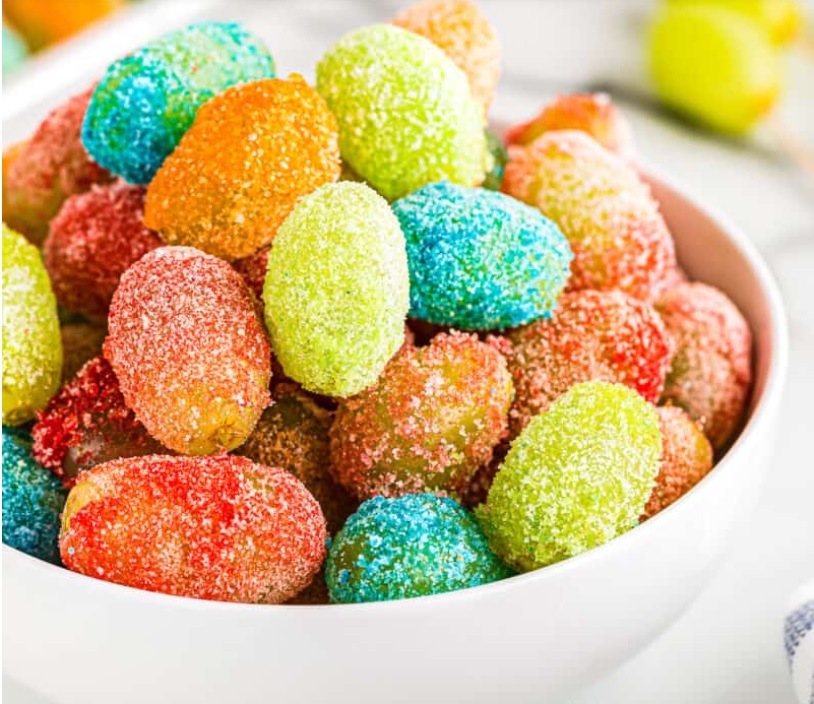 white bowl of brightly colored jello covered candy grapes