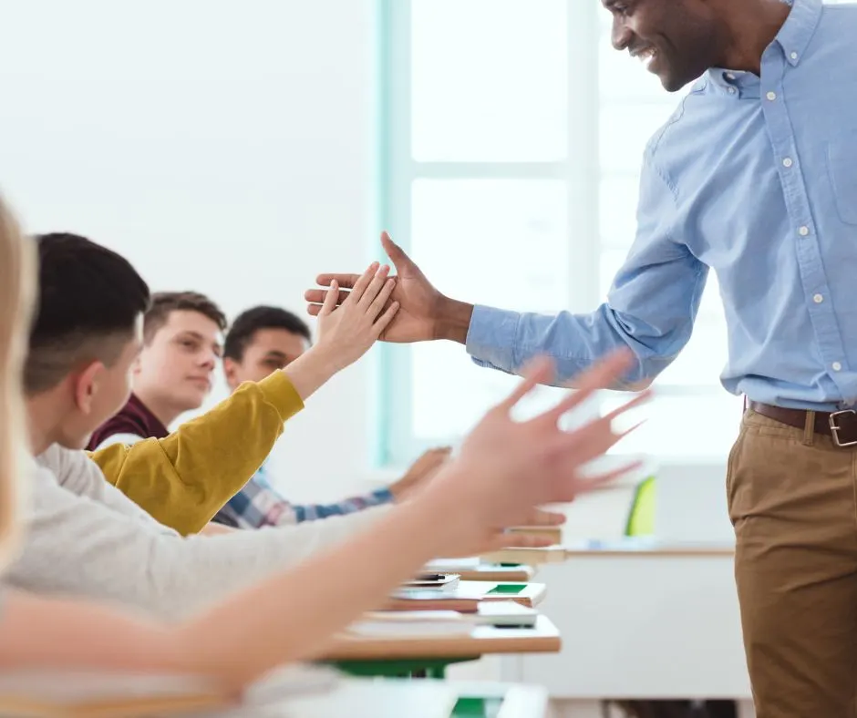 male teacher slapping high fives to students working on volunteer projects