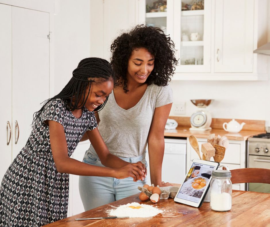 teen and tween sisters cracking an egg in kitchen and making a turkey cake, having fun