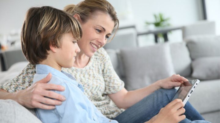 mother and son on couch looking at iphone investing stock apps for kids
