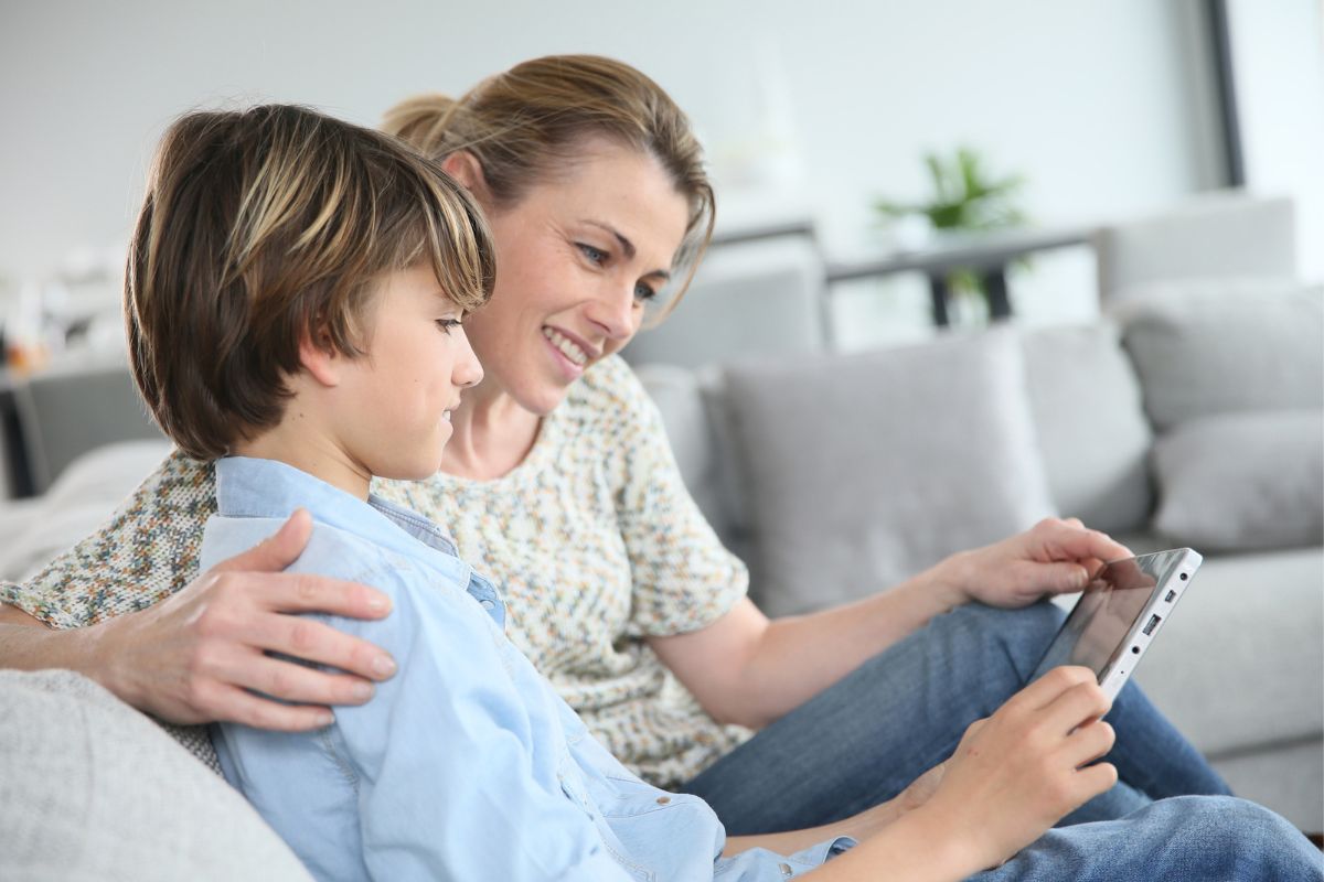 mother and son on couch looking at iphone investing stock apps for kids