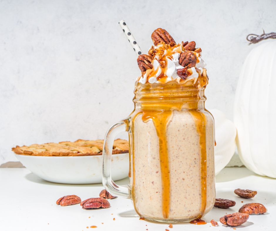 decadent pumpkin pie milkshake in mason jar with handle, with caramel and pecans on top