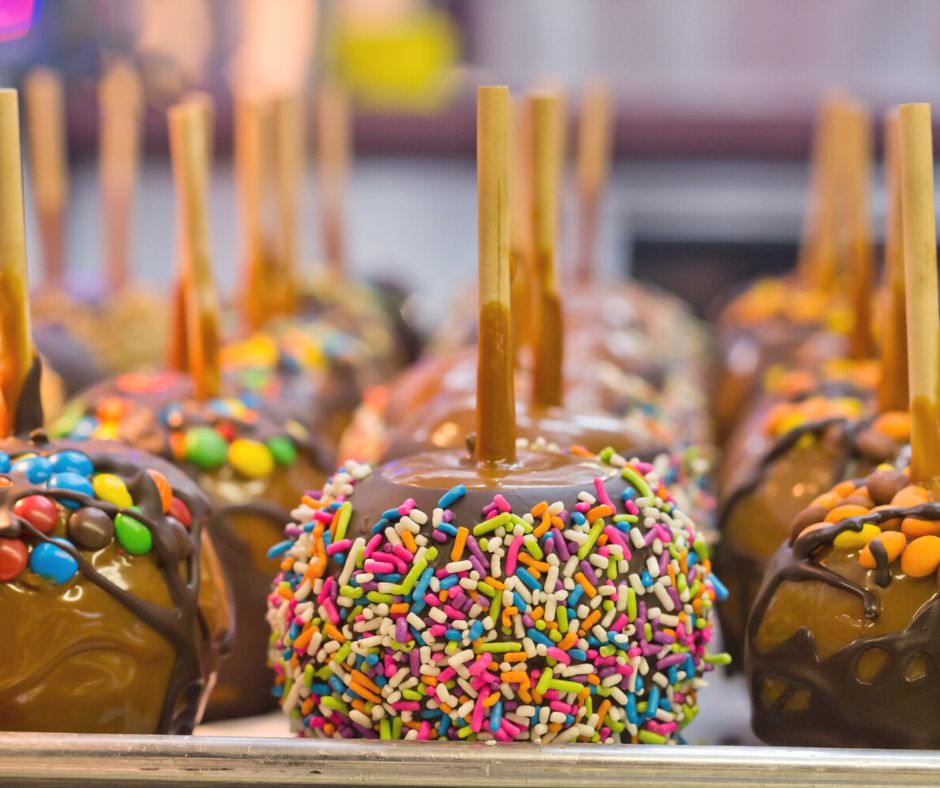 tray of chocolate covered apples with colorful sprinkles, candies, etc. on them