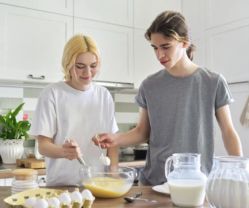 teen boy and girl in kitchen cooking pancakes for parents on thanksgiving