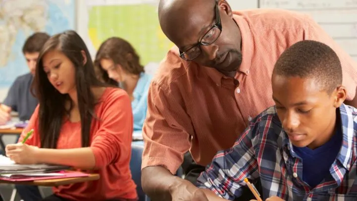 teacher looking over student's shoulder to help with teaching budgeting