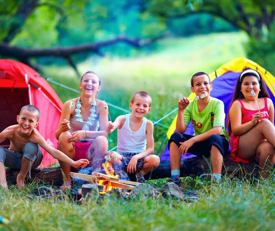 group of older kids with tents in backyard campout, eating marshmallows