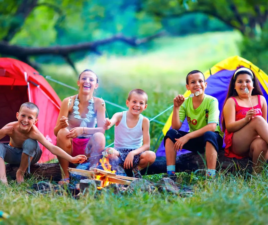 group of older kids with tents in backyard campout, eating marshmallows