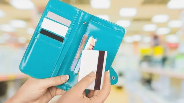 teal colored, bright wallet with teen girl putting card inside it