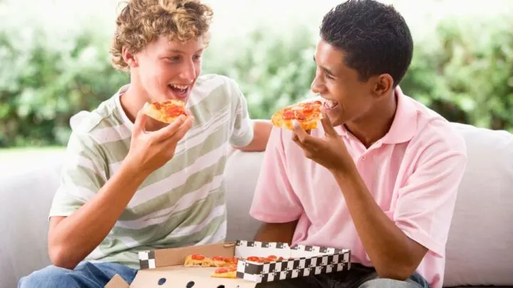 two boys eating pizza they bought together