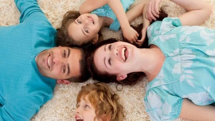 family of four on white carpeted floor having fun