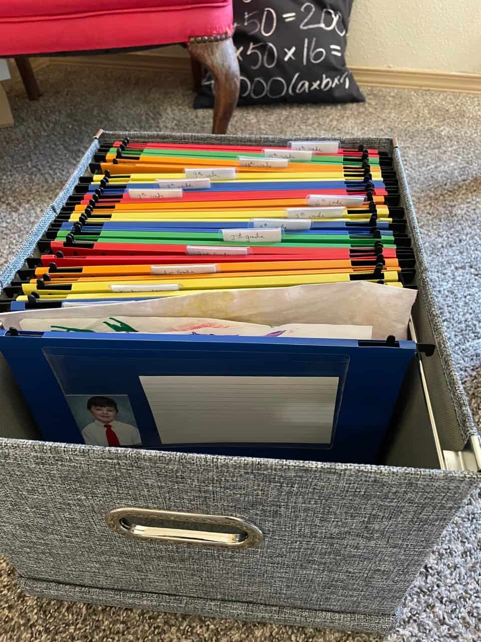 gray filing box filled with colorful folders for each grade, and a school picture of boy on outside
