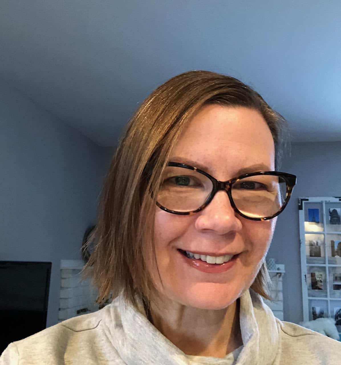 middle-aged woman in brown glasses with short crop hairstyle