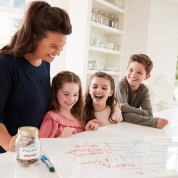 mother with three kids looking over chore chart on kitchen counter