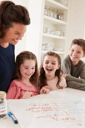 mother with three kids looking over chore chart on kitchen counter