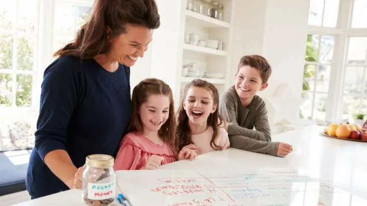 mother with three kids looking over chore chart on kitchen counter