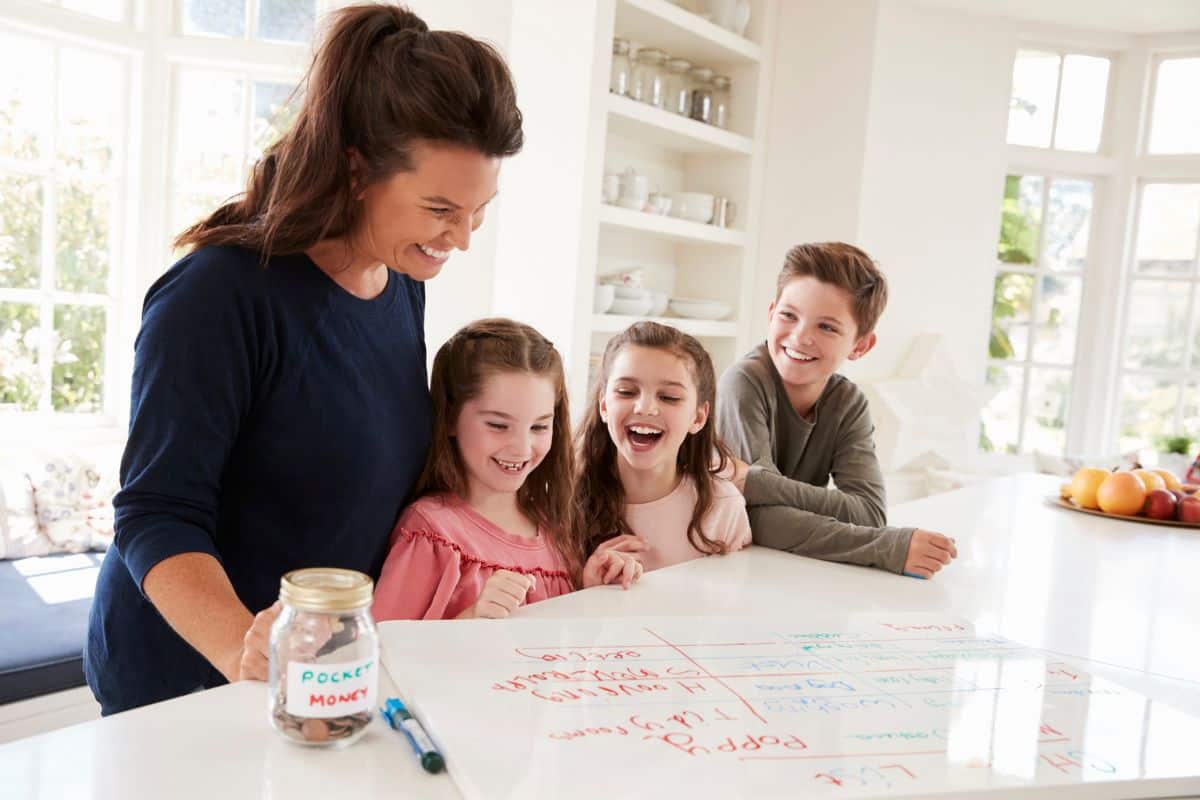 mother with three kids looking over chore chart on kitchen counter