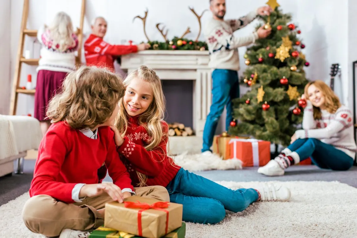 two kids doing Christmas activities with family in background, smiling