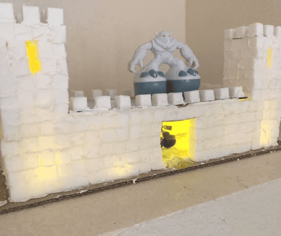 yeti figure on top of castle made out of sugar cubes and frosting, with lights inside