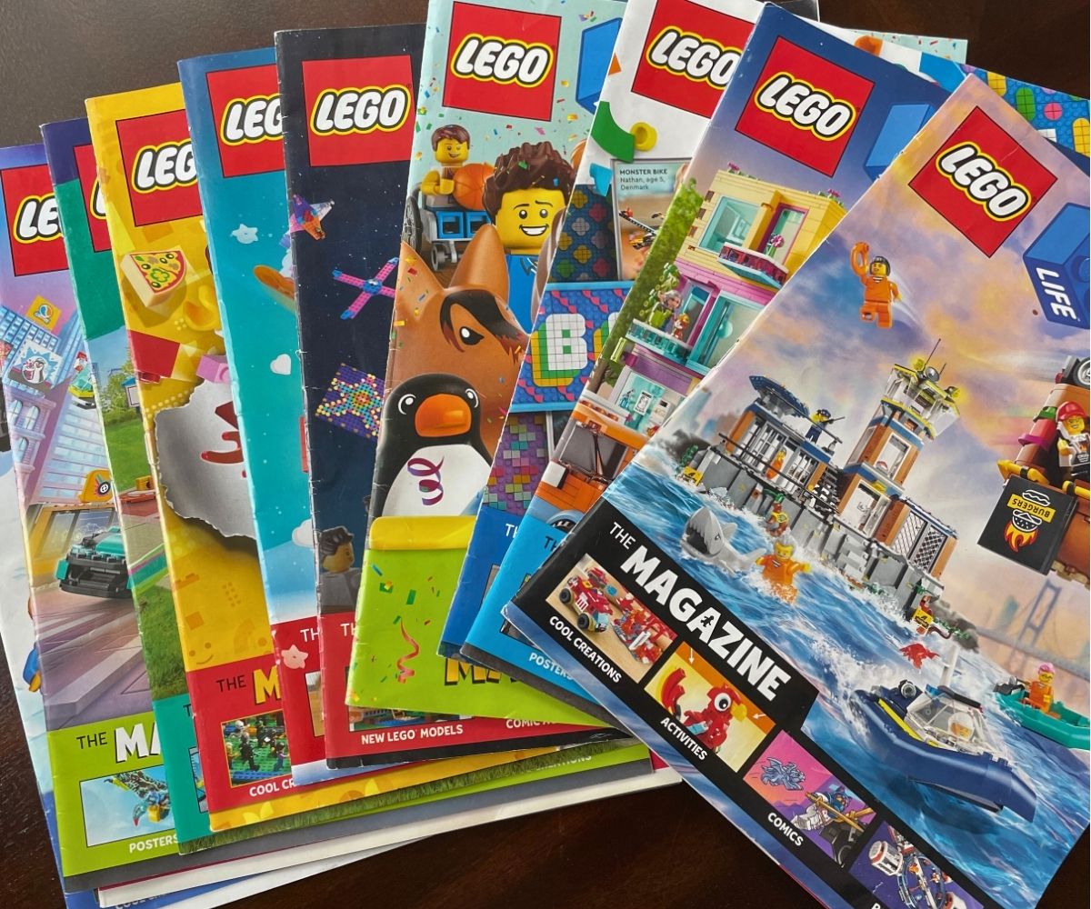 9 Lego Magazines splayed out on a dark wooden table
