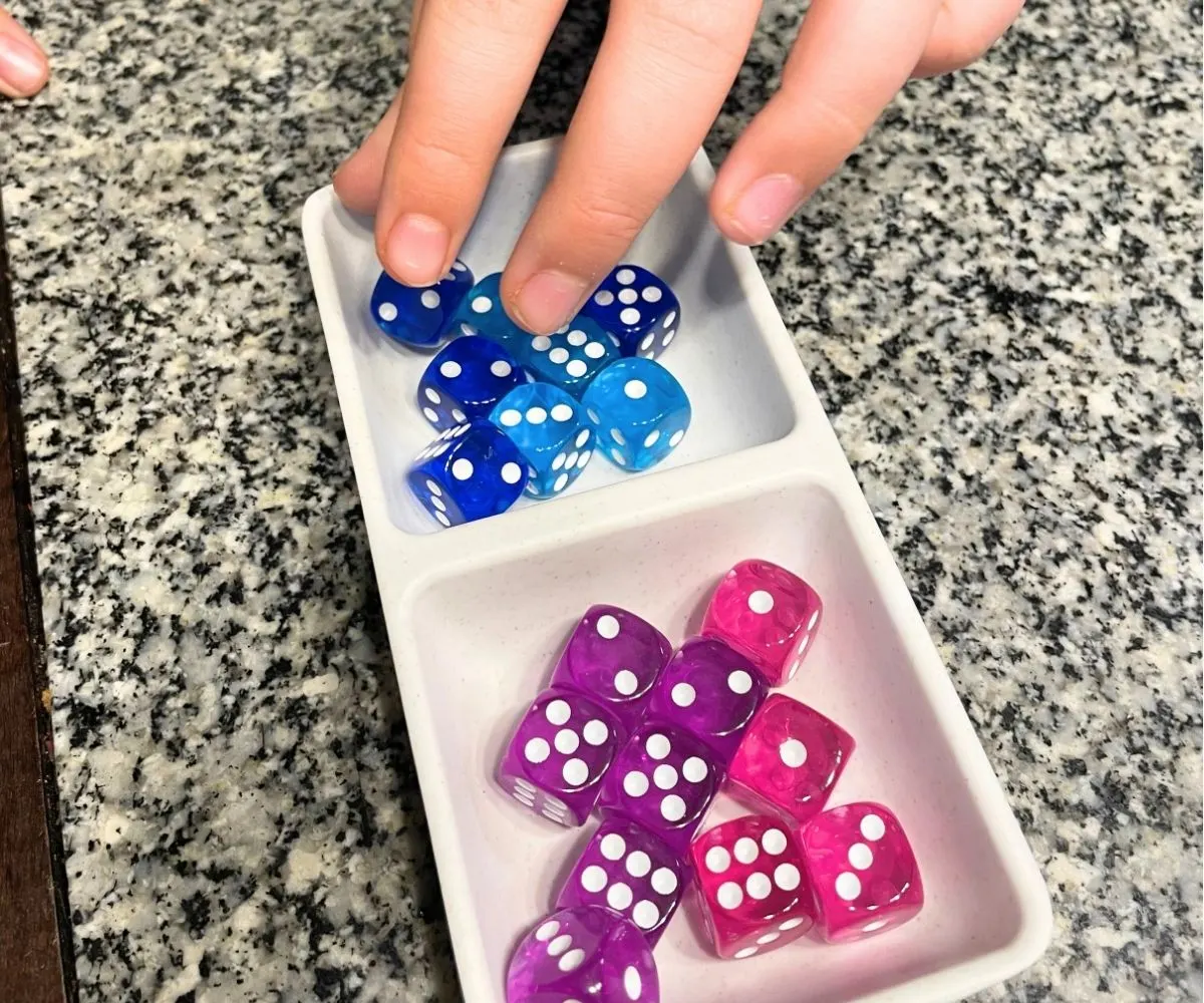 boy playing with very colorful dice in a dish