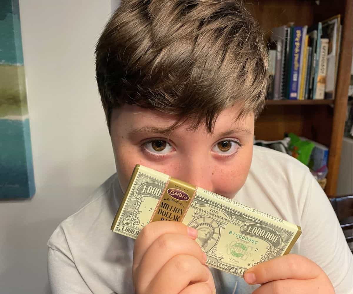 9 year old boy holding up a million dollar chocolate bar covering his face