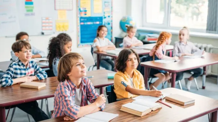 classroom of older elementary students smiling and looking ahead at teacher