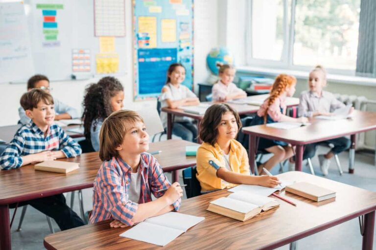 classroom of older elementary students smiling and looking ahead at teacher