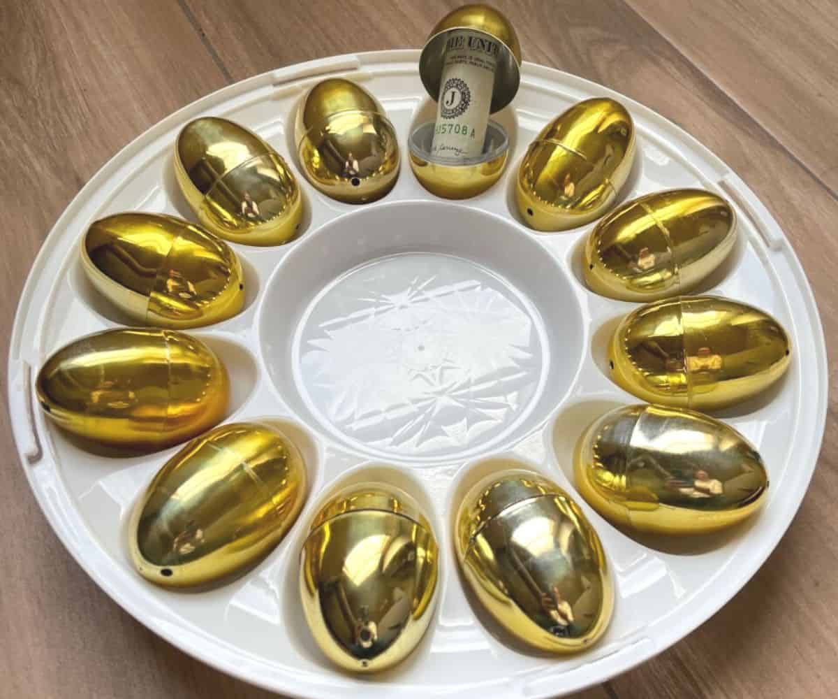 white devilled egg holder filled with golden easter eggs, and one egg open showing dollar bill