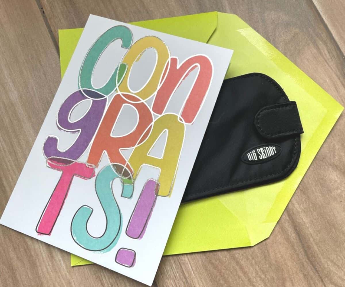slim black wallet sticking out of congrats graduation card with light green envelope