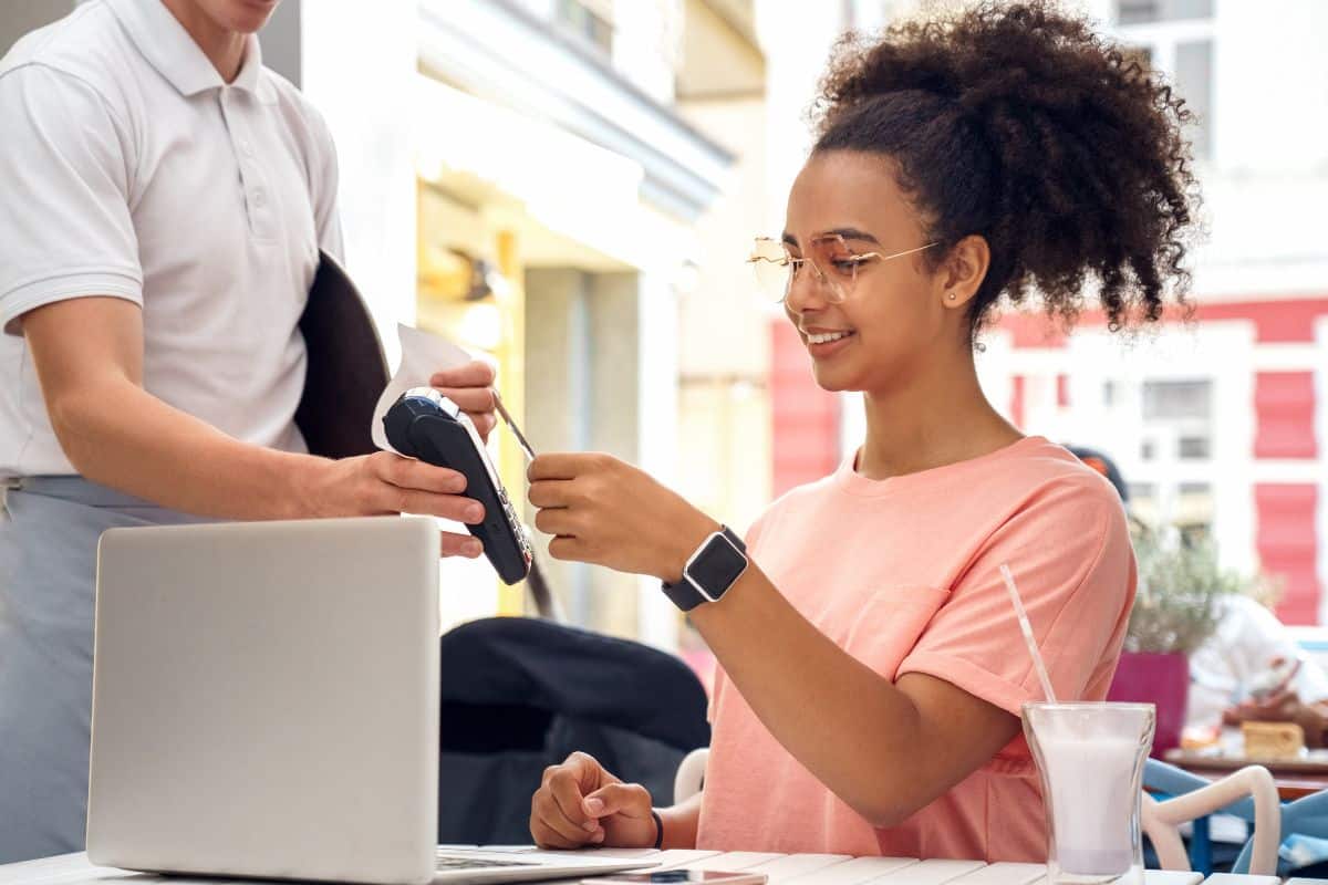 teen girl using debit card at restaurant to pay