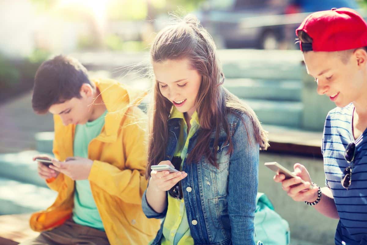 teen girl and boy on bleachers transferring money through an app