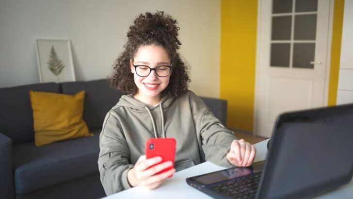 teen girl with red phone making a trade on stock app for teens