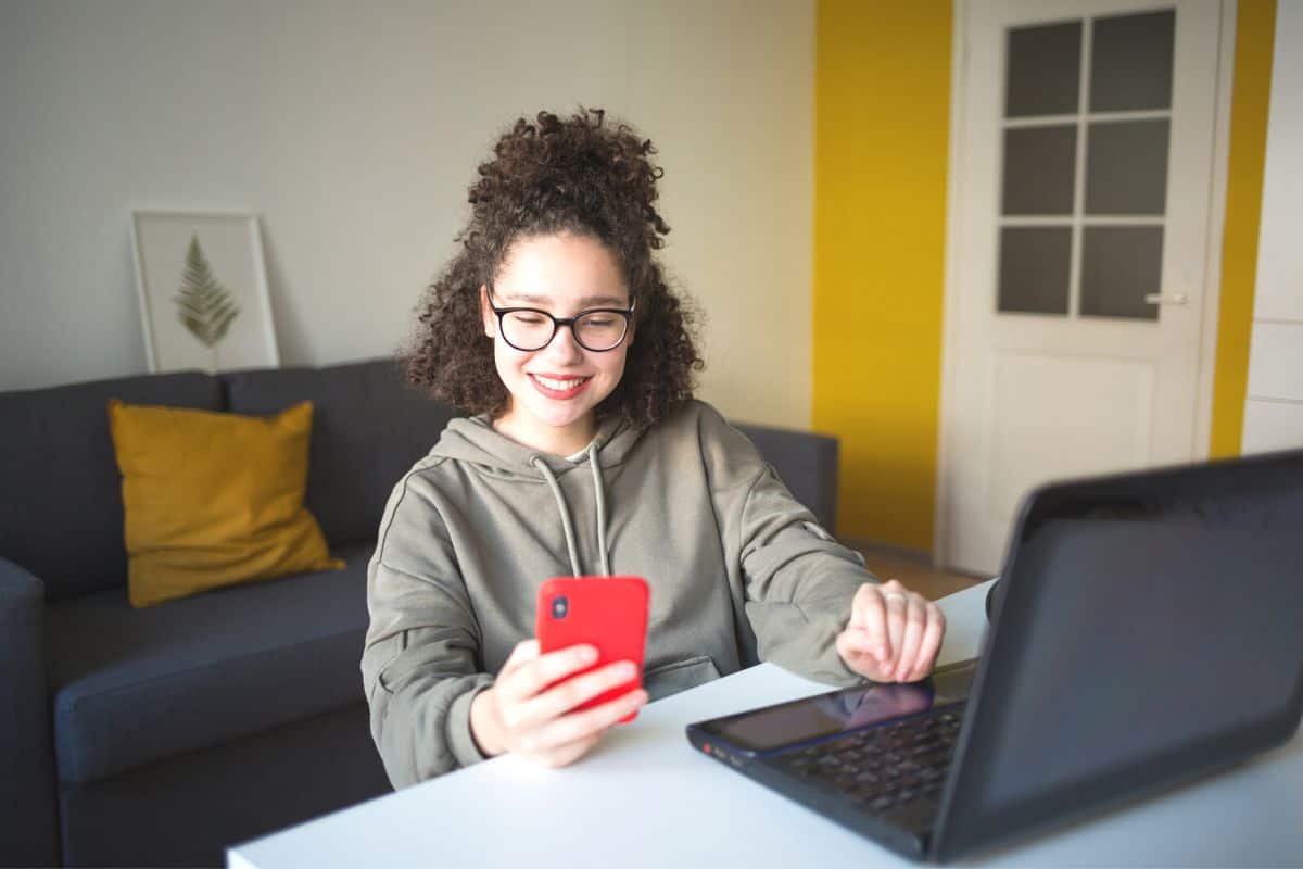 teen girl with red phone making a trade on stock app for teens