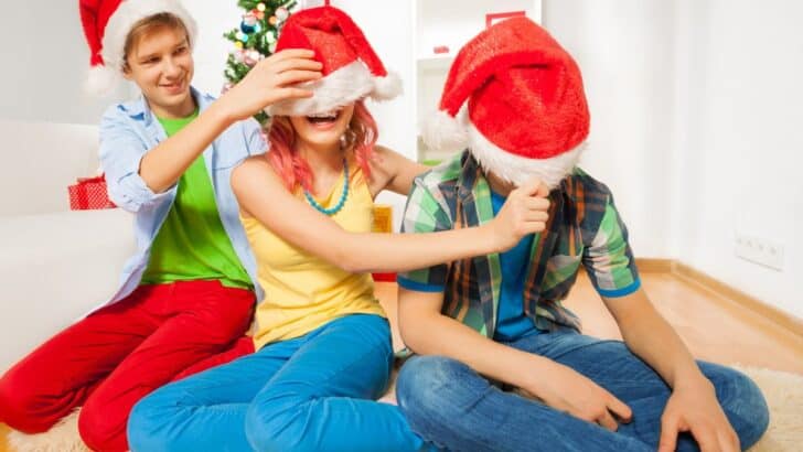 three teens in santa hats at home having fun