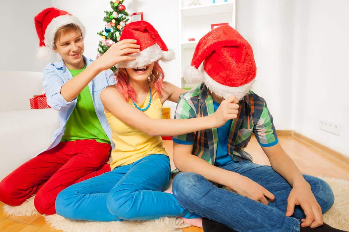 three teens in santa hats at home having fun