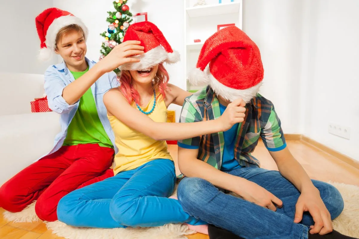 three teens in santa hats at home having fun