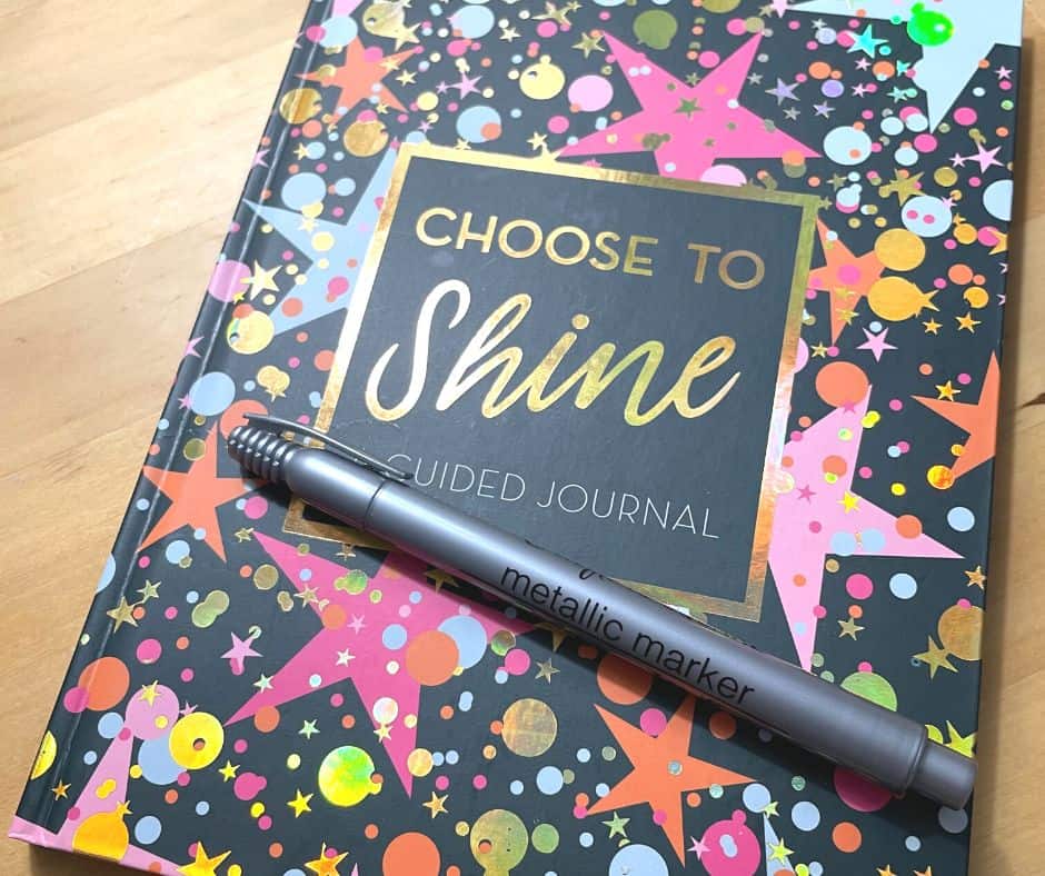 bright journal says "choose to shine" with metallic marker laying on front