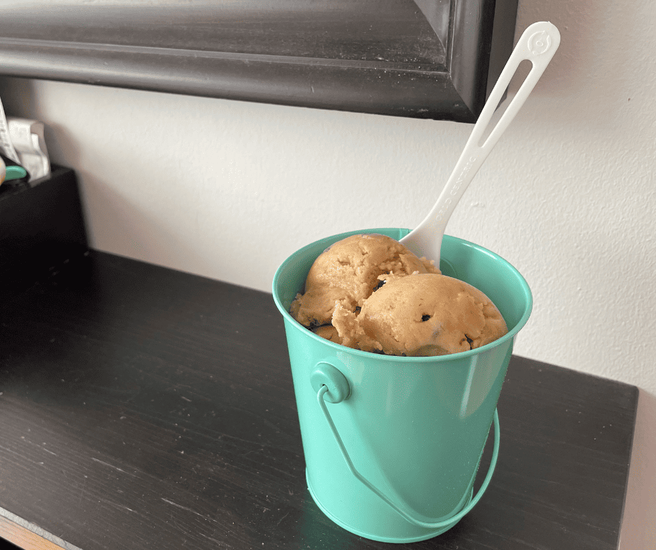 light teal tin of ice-cream scooped raw cookie dough on black table