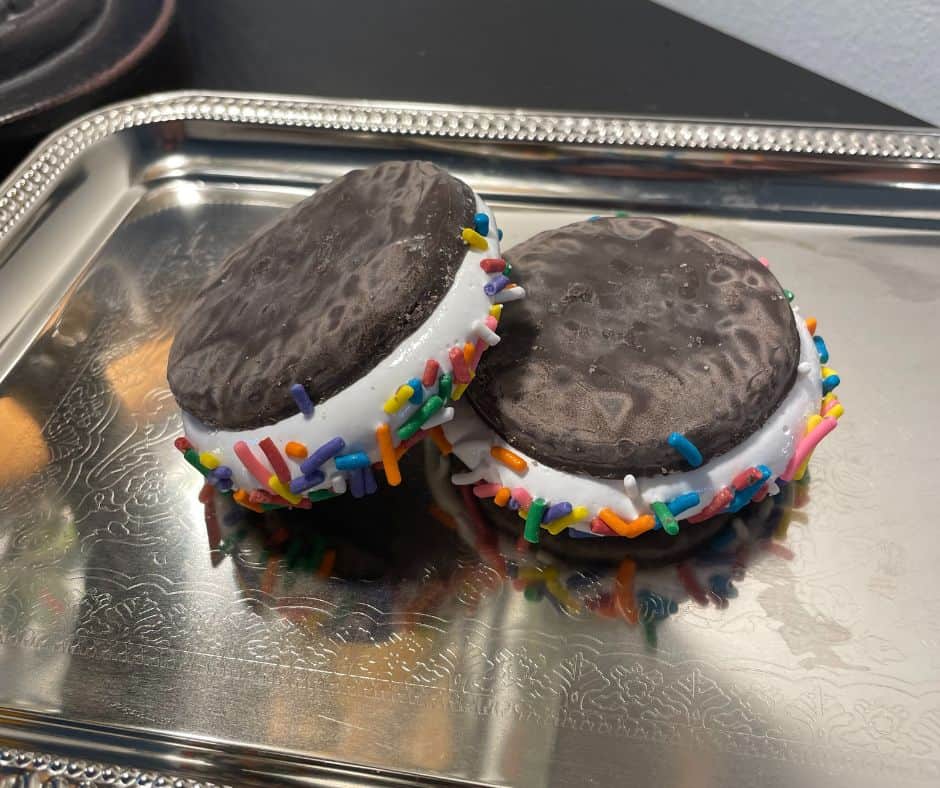 black cookie sandwiches with rainbow sprinkles on marshmallow cream, on silver tray