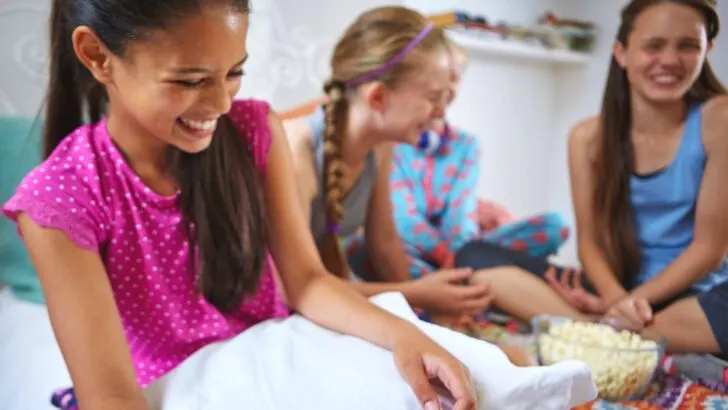 group of girls in colorful shirts at sleepover, hilariously laughing