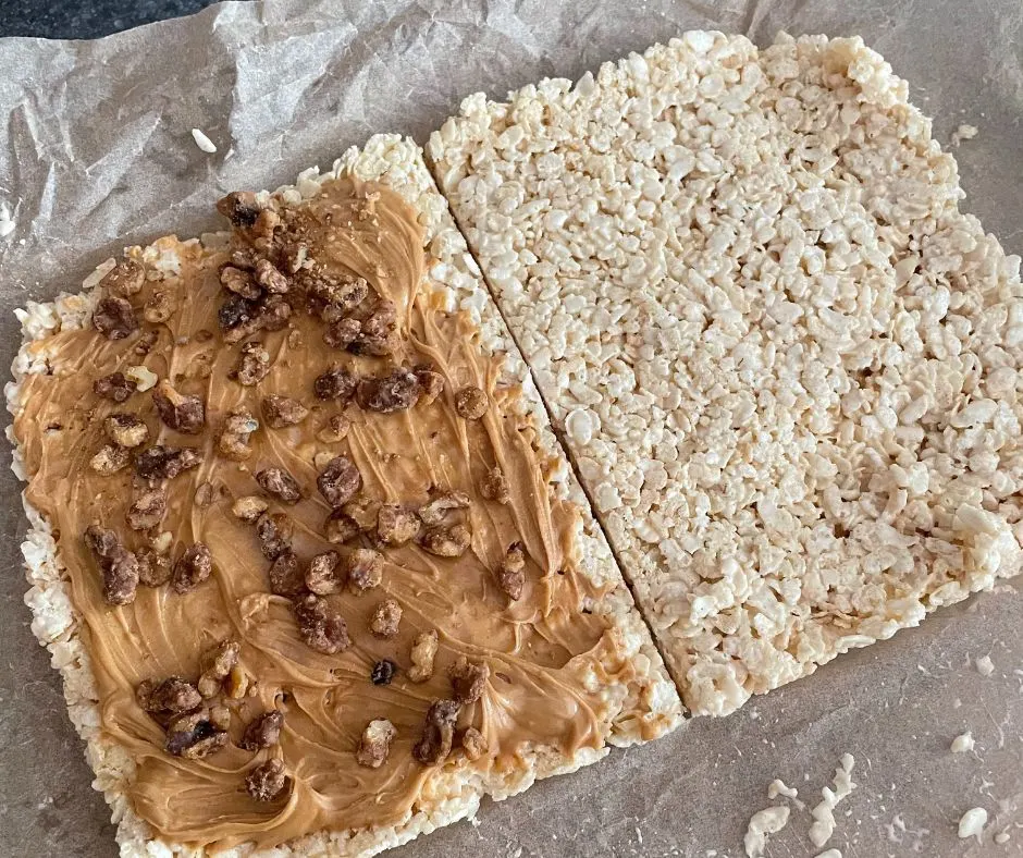 pan of rice krispy treats cut in half, then one side has peanut butter and maple walnuts on it