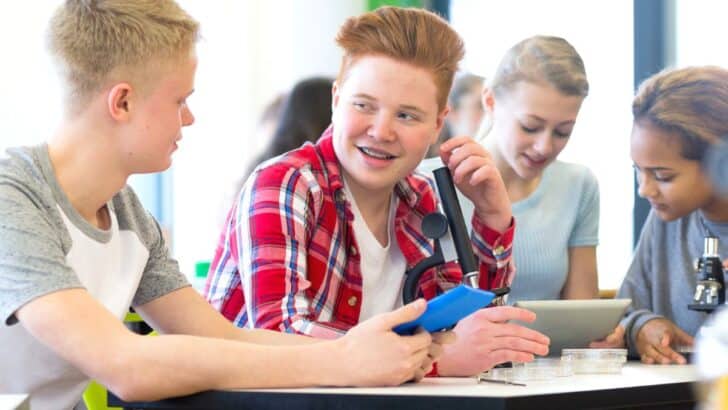 two teen students in class smiling, talking through would you rather questions for teen students